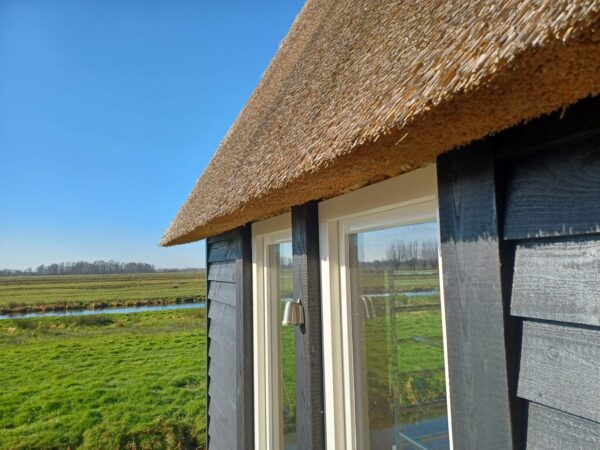 Dezente schöne kleine Außenwandleuchte am Reetdachhaus zwischen den Fenster